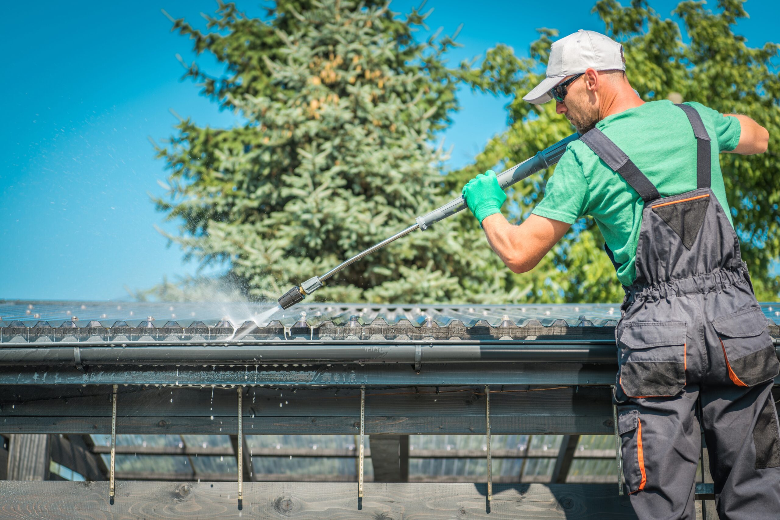 Handy Andy technician cleaning roof and gutters on house using pressure washer in Seattle Washington